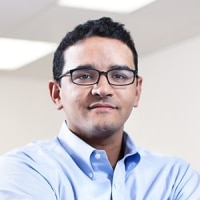 A person wearing glasses and a shirt and tie.